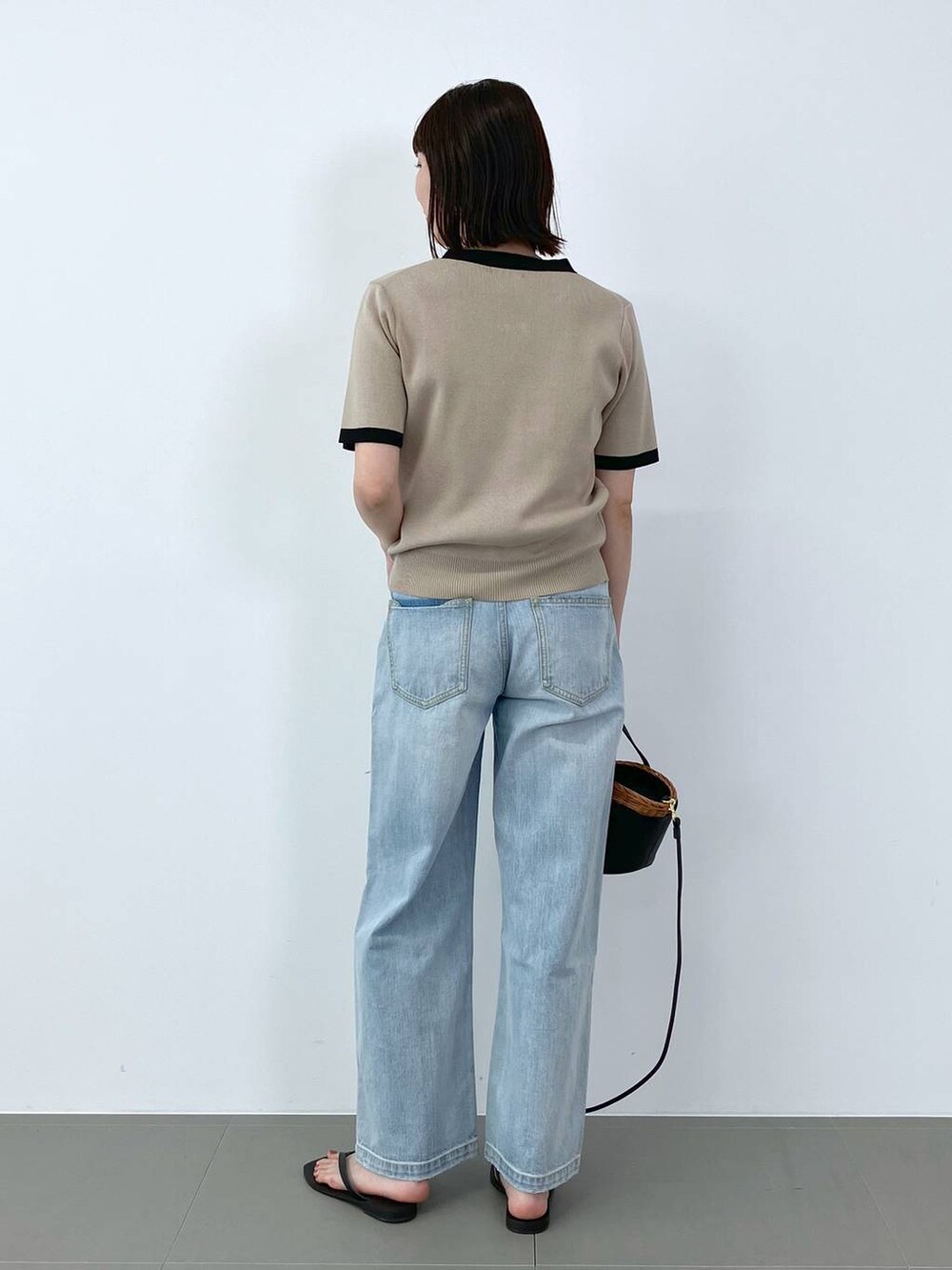 ブラック系のかごバッグ、ブルー系のデニムパンツ、ブラック系のサンダルを着用したレディースの夏コーディネートの3枚目の写真