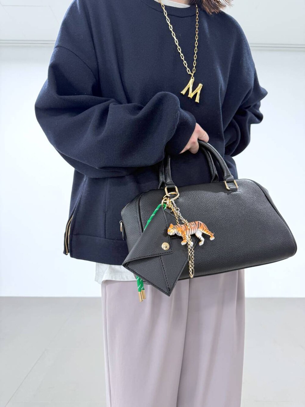 ホワイト系のTシャツ/カットソー、ブラック系のボストンバッグ、ベージュ系のスラックスを着用したレディースの冬コーディネートの4枚目の写真