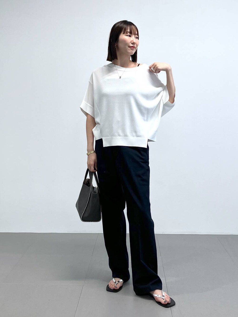 グレー系のトートバッグ、その他のサンダル、ブルー系のチノパンツを着用したレディースの夏コーディネートの2枚目の写真