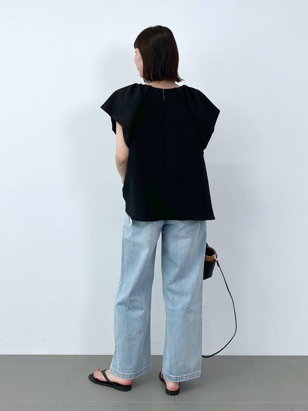 ブラック系のシャツ/ブラウス、ブラック系のかごバッグ、ブルー系のデニムパンツを着用したレディースの夏コーディネートの5枚目の写真