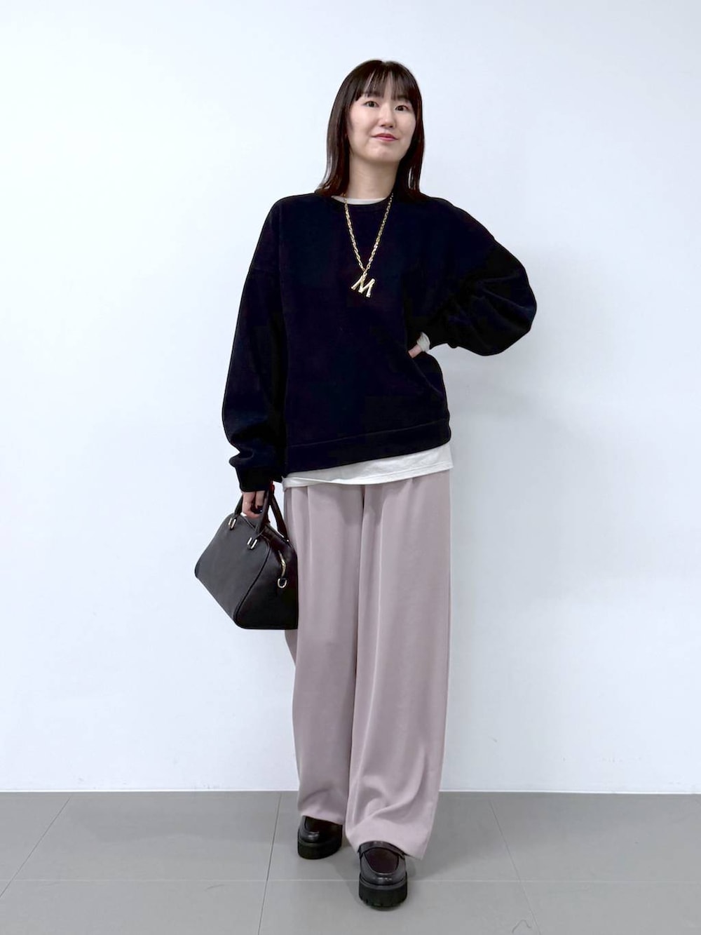 ホワイト系のTシャツ/カットソー、ブラック系のボストンバッグ、ベージュ系のスラックスを着用したレディースの冬コーディネートの2枚目の写真