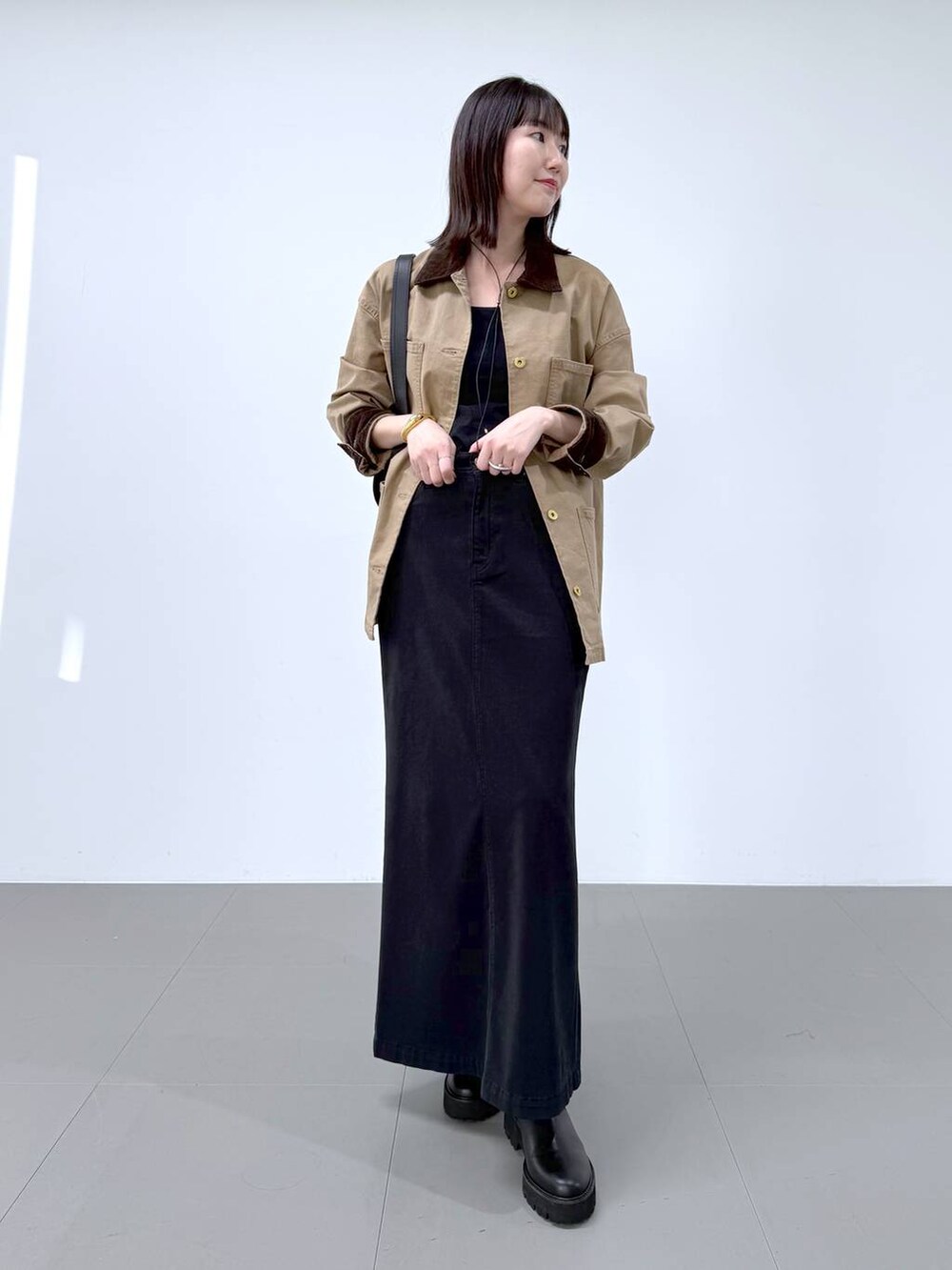 ブラック系のスカート、その他のブーツ、ブラック系のショルダーバッグを着用したレディースの冬コーディネートの2枚目の写真