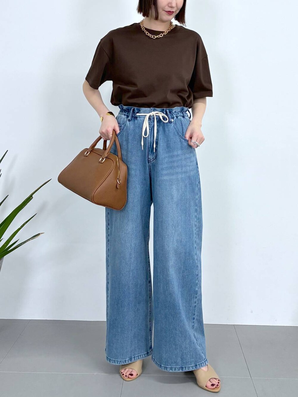 ブラウン系のボストンバッグ、ブルー系のデニムパンツ、ブラウン系のTシャツ/カットソーを着用したレディースの春コーディネートの6枚目の写真