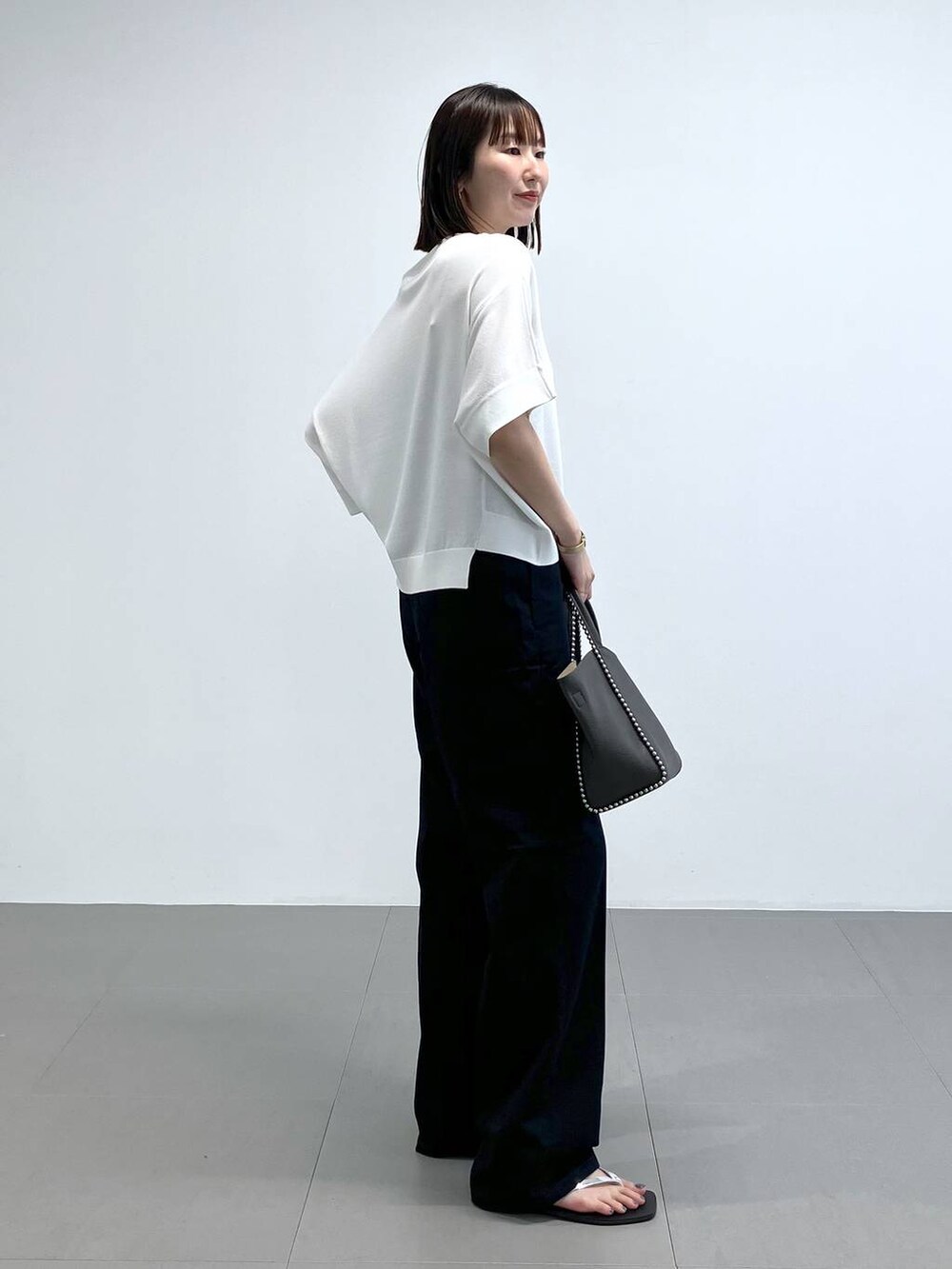 グレー系のトートバッグ、その他のサンダル、ブルー系のチノパンツを着用したレディースの夏コーディネートの4枚目の写真