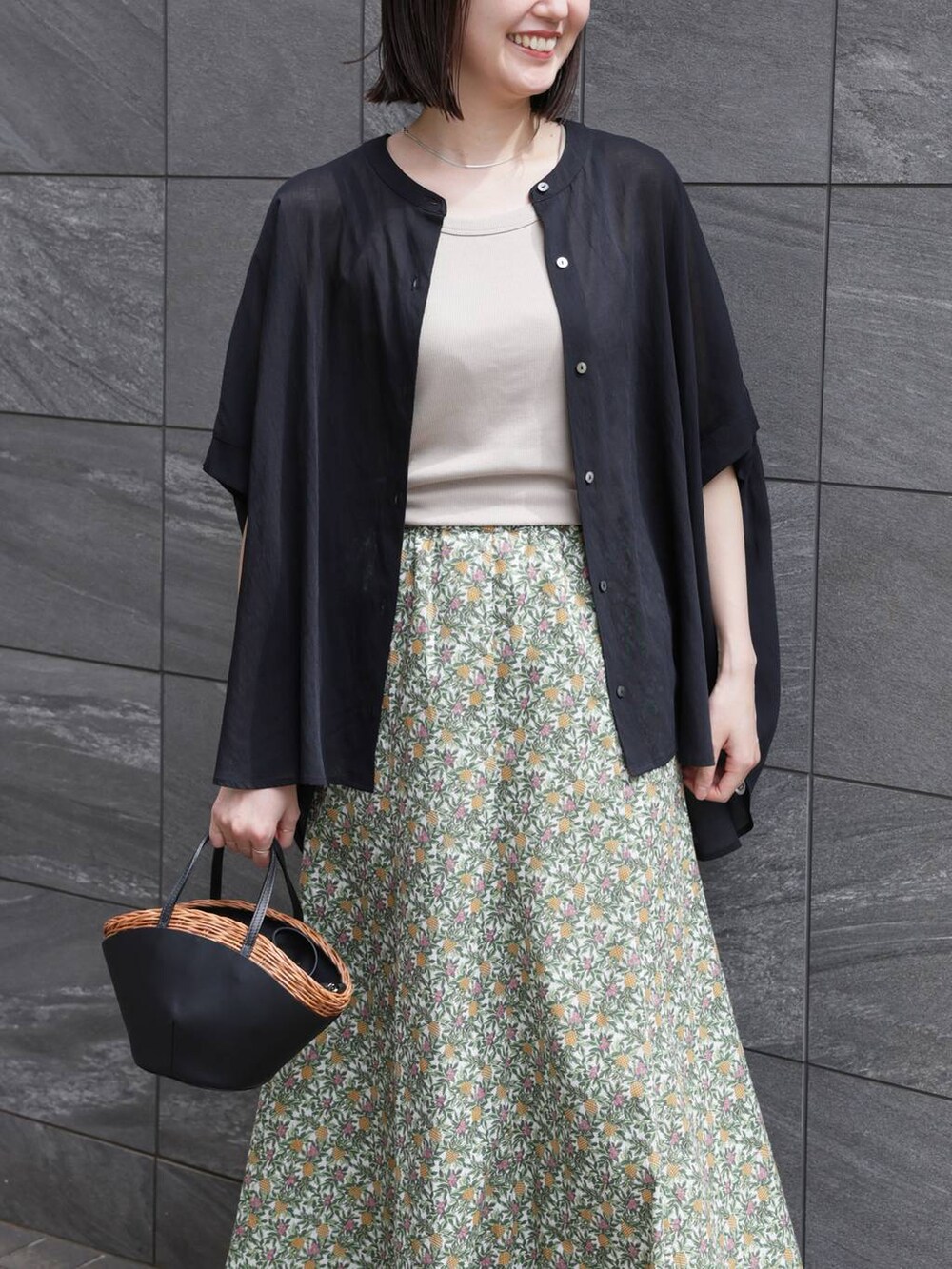 ホワイト系のスカート、ブラック系のかごバッグ、ブラック系のシャツ/ブラウスを着用したレディースの夏コーディネートの3枚目の写真