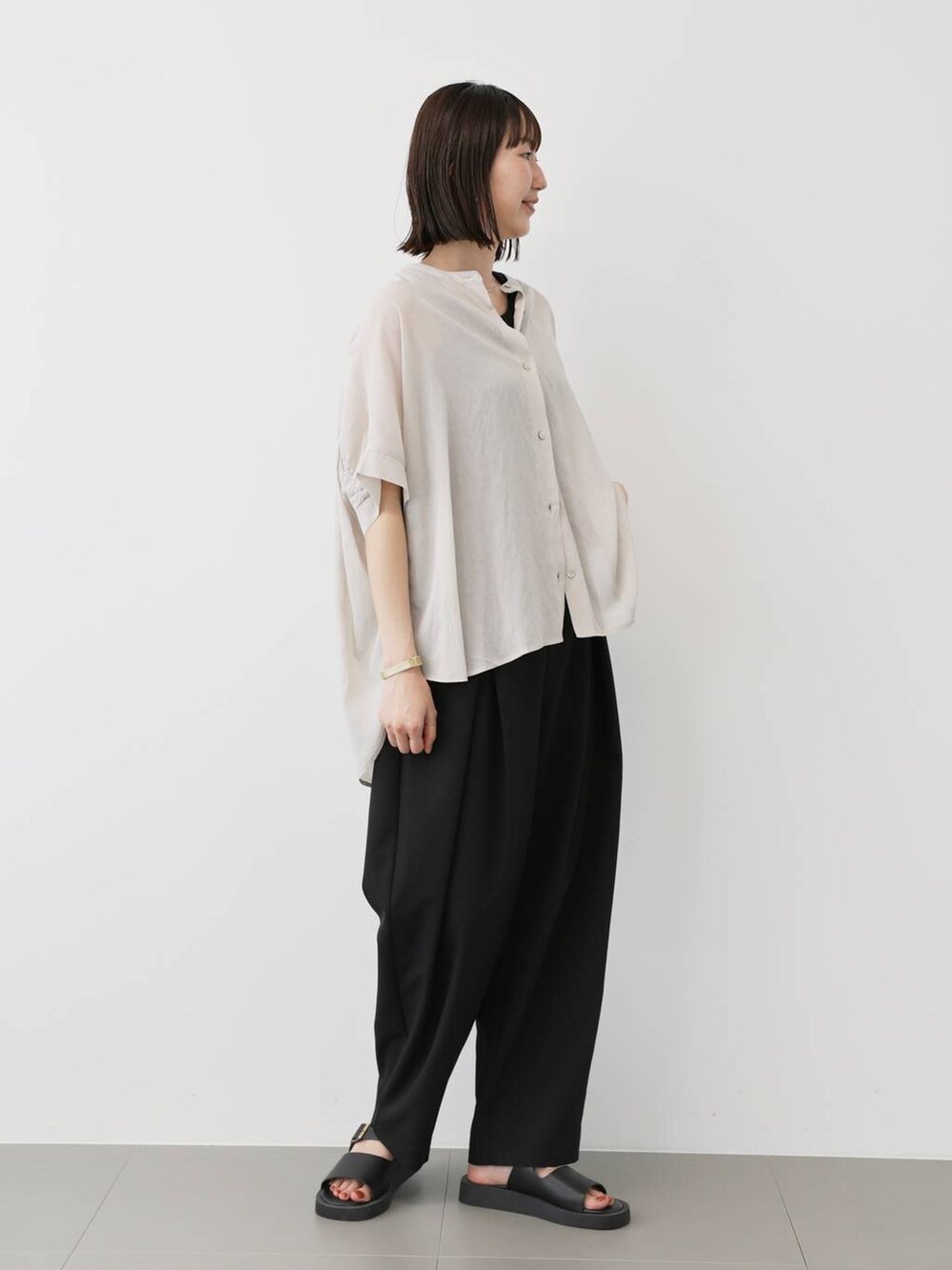 ブラック系のスラックス、ブラック系のタンクトップ、ホワイト系のシャツ/ブラウスを着用したレディースの夏コーディネートの2枚目の写真