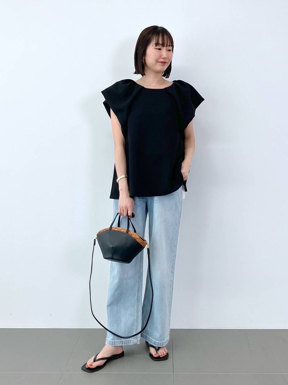 ブラック系のシャツ/ブラウス、ブラック系のかごバッグ、ブルー系のデニムパンツを着用したレディースの夏コーディネートの2枚目の写真