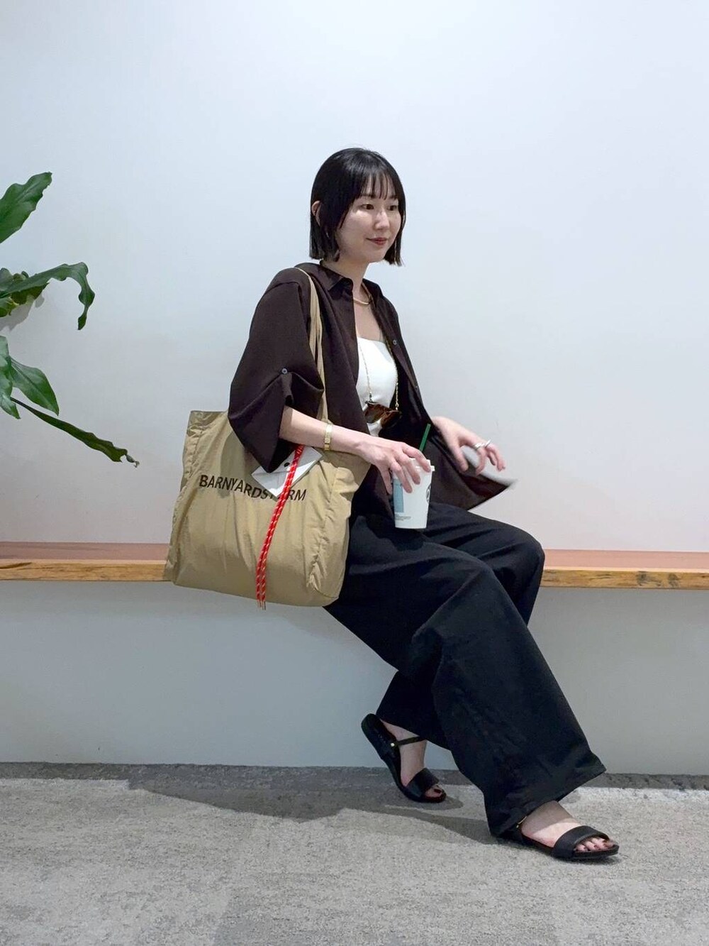 ブラック系のデニムパンツ、ベージュ系のトートバッグ、ブラウン系のシャツ/ブラウスを着用したレディースの春コーディネートの3枚目の写真