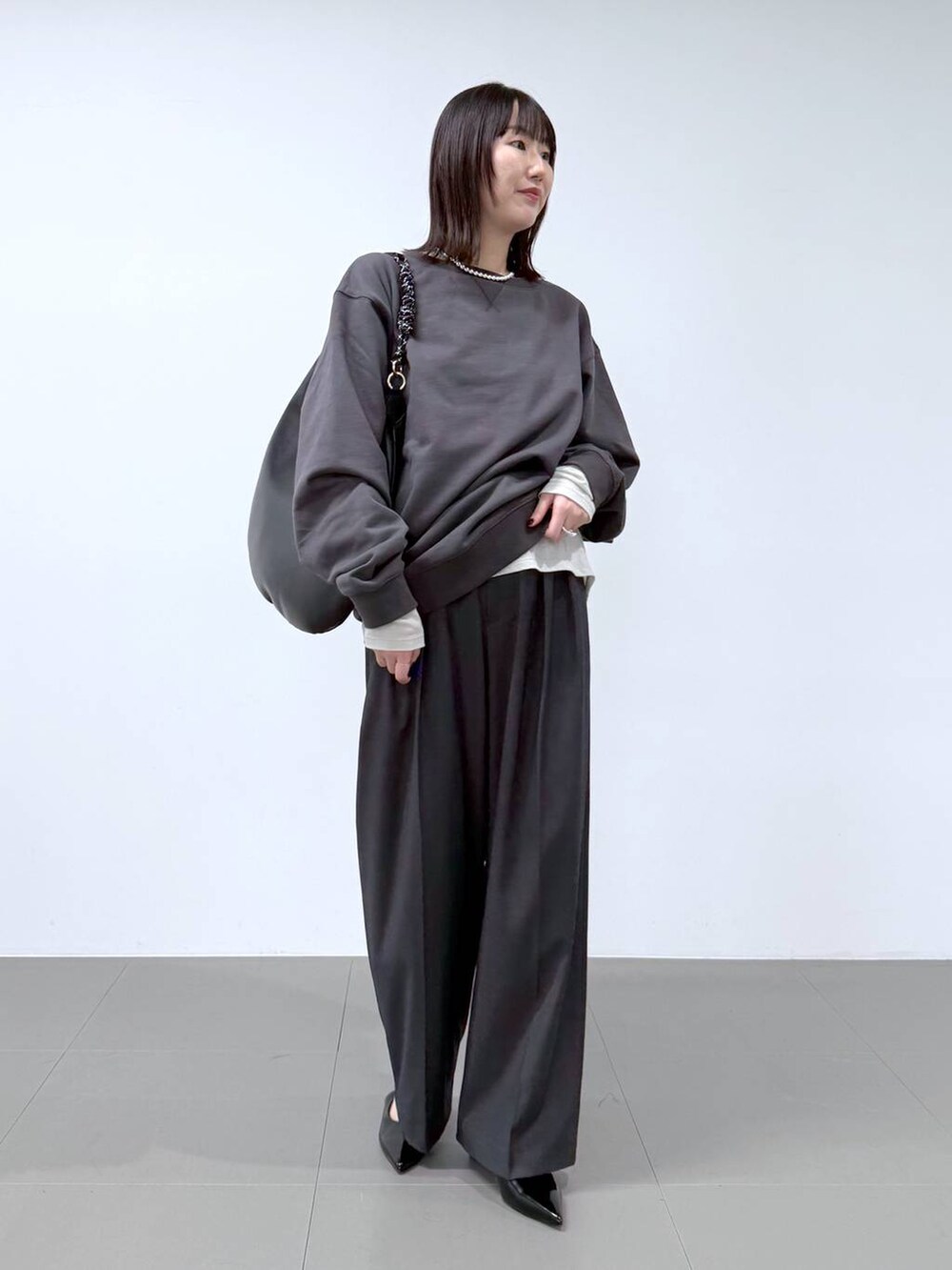 グレー系のTシャツ/カットソー、グレー系のスラックス、グレー系のスウェットを着用したレディースの冬コーディネートの2枚目の写真