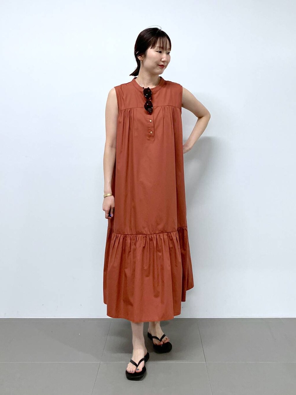 ブラック系のサンダル、オレンジ系のワンピースを着用したレディースの夏コーディネートの2枚目の写真