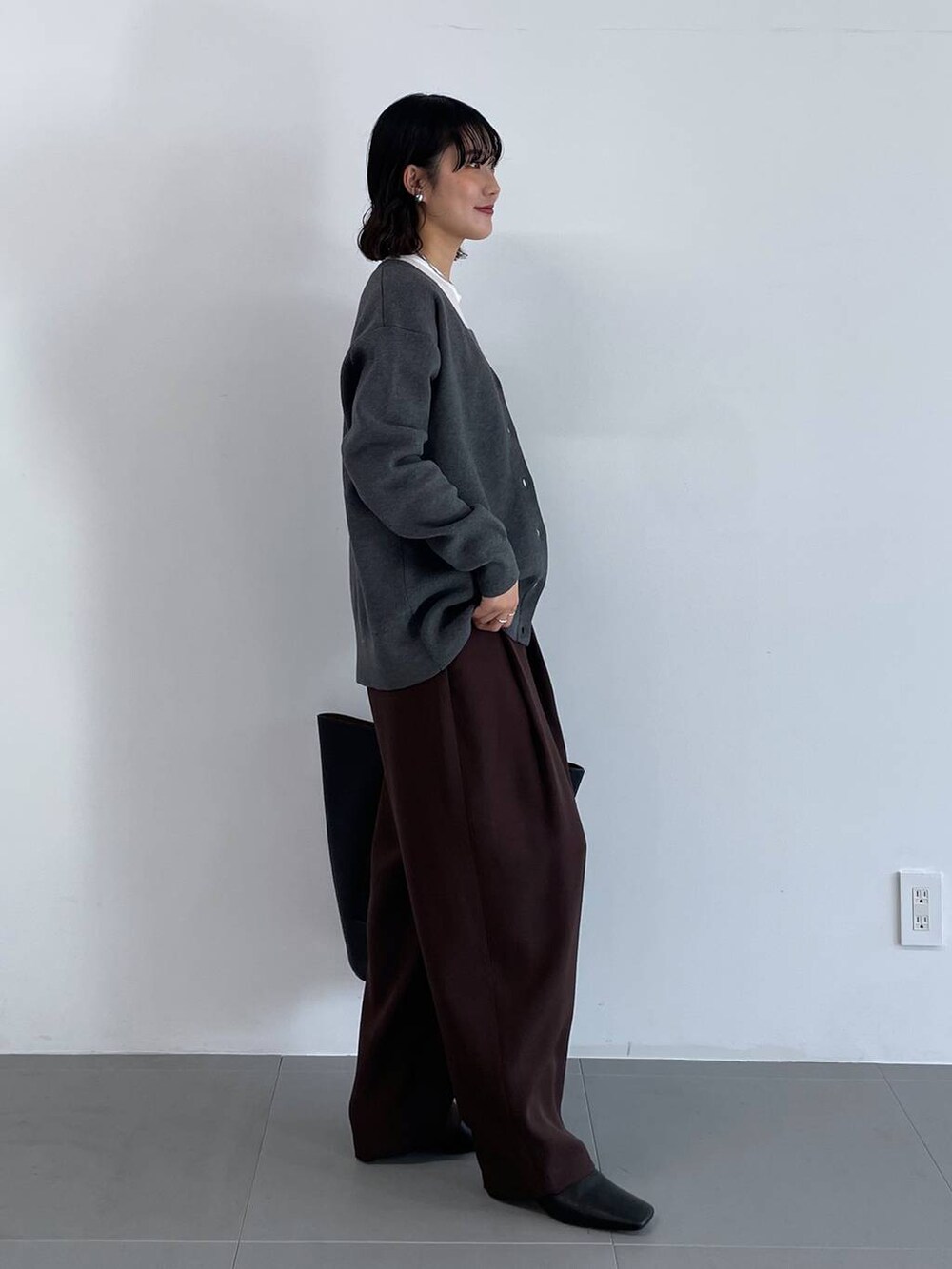 ブラック系のトートバッグ、ブラウン系のその他パンツ、グレー系のカーディガン/ボレロを着用したレディースの冬コーディネートの3枚目の写真
