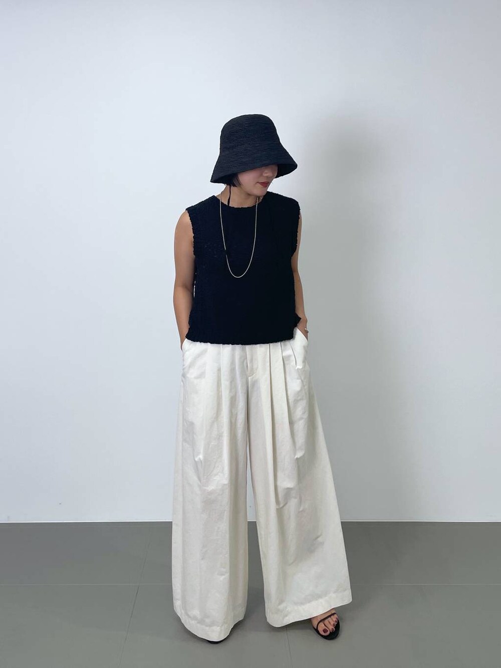 ブラック系のニット/セーター、ホワイト系のその他パンツ、ブラック系のハットを着用したレディースの春コーディネートの2枚目の写真