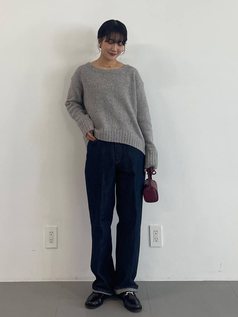 レッド系のショルダーバッグ、ブラック系のローファー、ブルー系のデニムパンツを着用したレディースの冬コーディネートの2枚目の写真