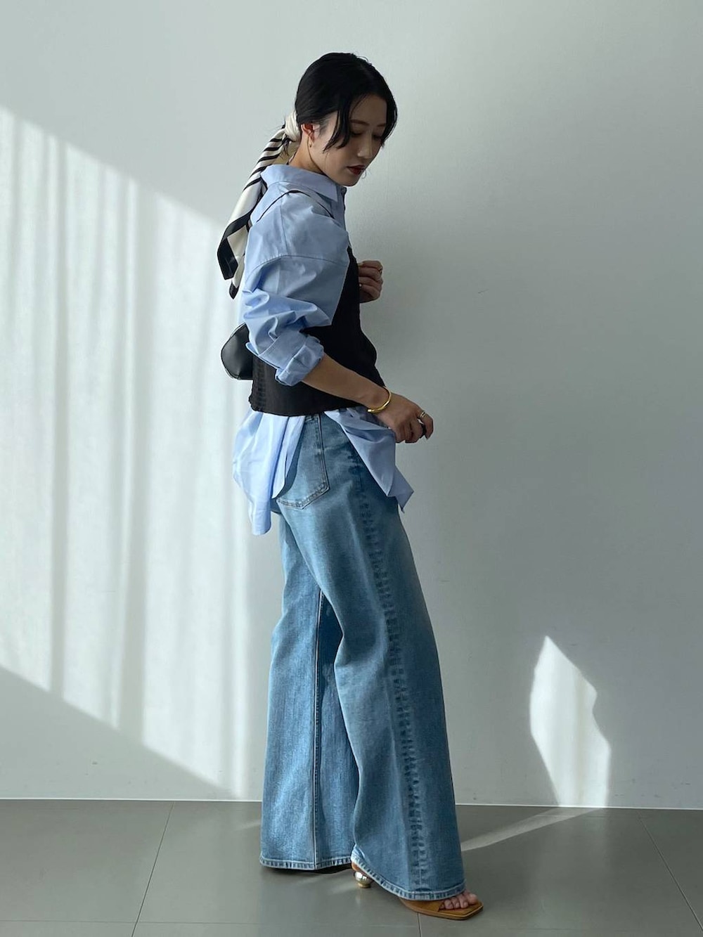 ブラック系のハンドバッグ、ブルー系のシャツ/ブラウス、ブルー系のデニムパンツを着用したレディースの冬コーディネートの3枚目の写真