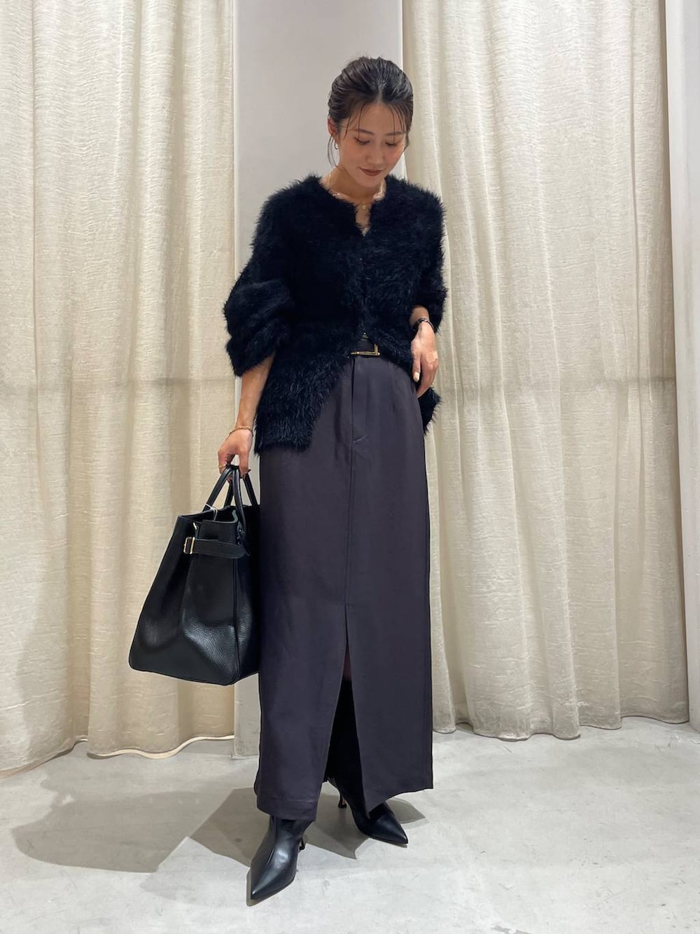 ブラック系のカーディガン/ボレロ、グレー系のスカート、ブラック系のハンドバッグを着用したレディースの秋コーディネートの2枚目の写真