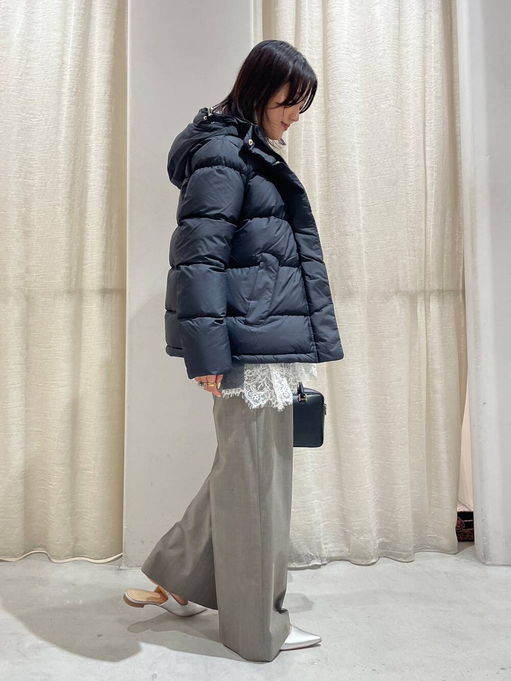 グレー系のスラックス、グレー系のニット/セーター、ホワイト系のキャミソールを着用したレディースの秋コーディネートの2枚目の写真