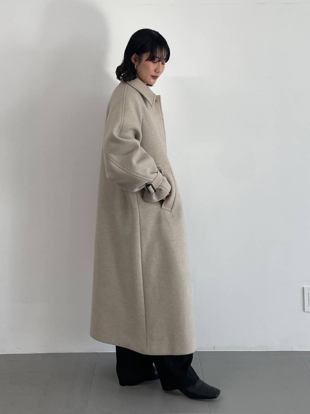 ブラック系のその他パンツ、ベージュ系のステンカラーコート、ベージュ系のニット/セーターを着用したレディースの冬コーディネートの3枚目の写真