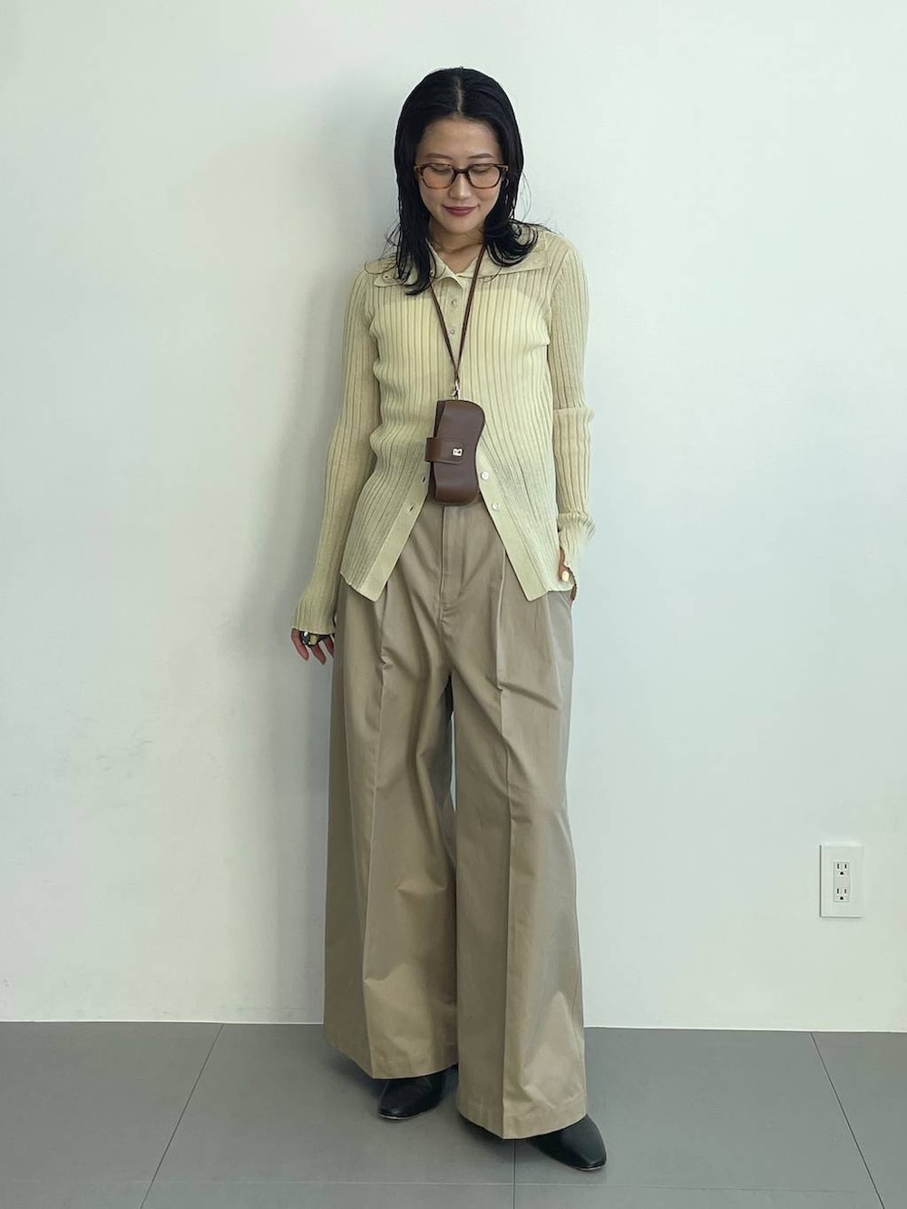 ブラック系のブーツ、ベージュ系のチノパンツ、イエロー系のニット/セーターを着用したレディースの冬コーディネートの2枚目の写真