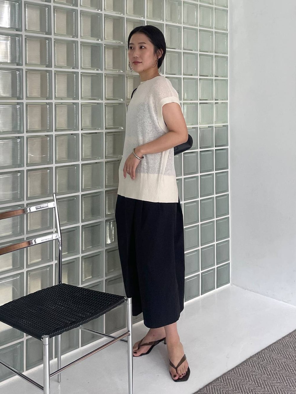 ブラック系のハンドバッグ、ブラック系のその他パンツ、ホワイト系のニット/セーターを着用したレディースの夏コーディネートの3枚目の写真