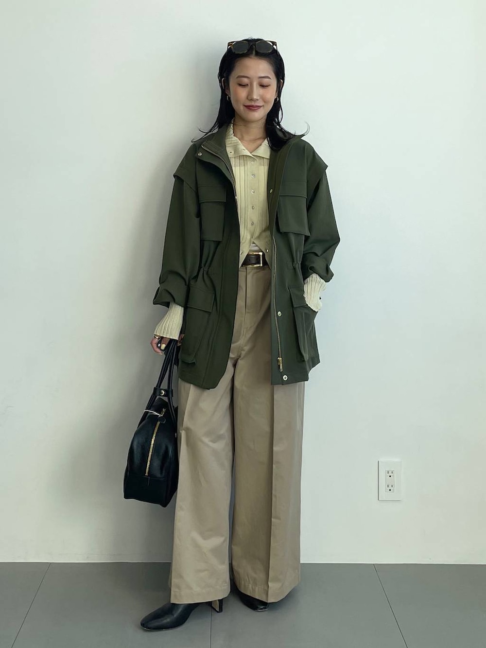 ブラック系のブーツ、ベージュ系のチノパンツ、イエロー系のニット/セーターを着用したレディースの冬コーディネートの3枚目の写真