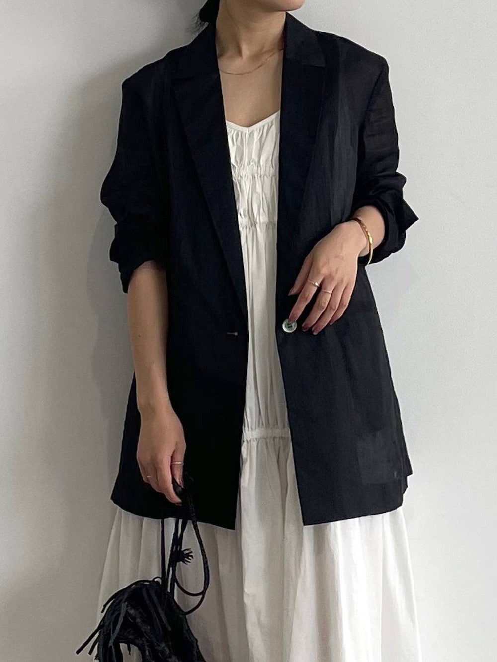 ホワイト系のサンダル、ホワイト系のワンピース、ブラック系のテーラードジャケットを着用したレディースの春コーディネートの3枚目の写真