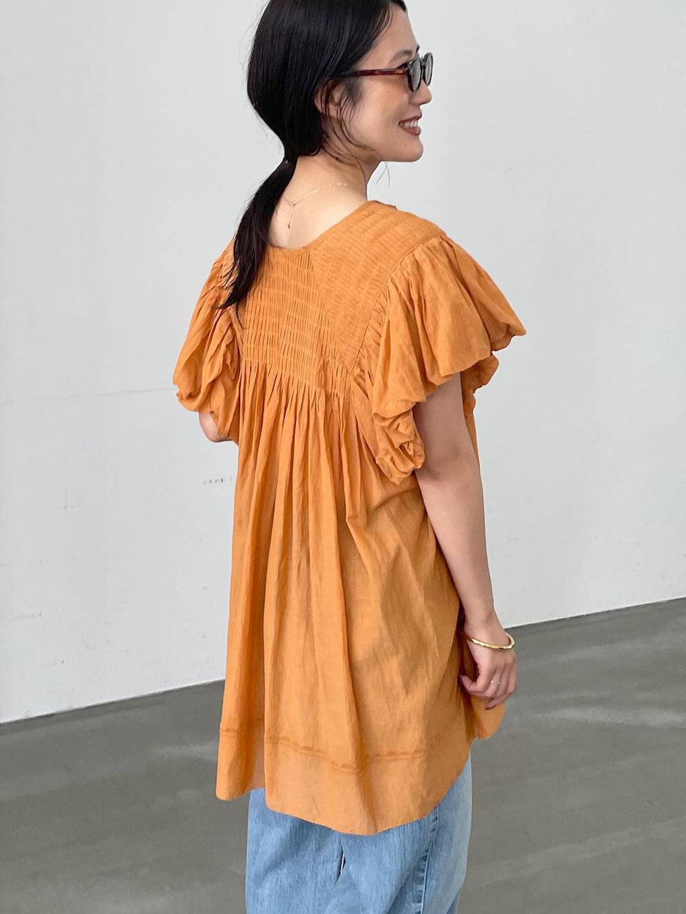 ベージュ系のTシャツ/カットソー、ブルー系のデニムパンツ、ブラウン系のサンダルを着用したレディースの夏コーディネートの5枚目の写真