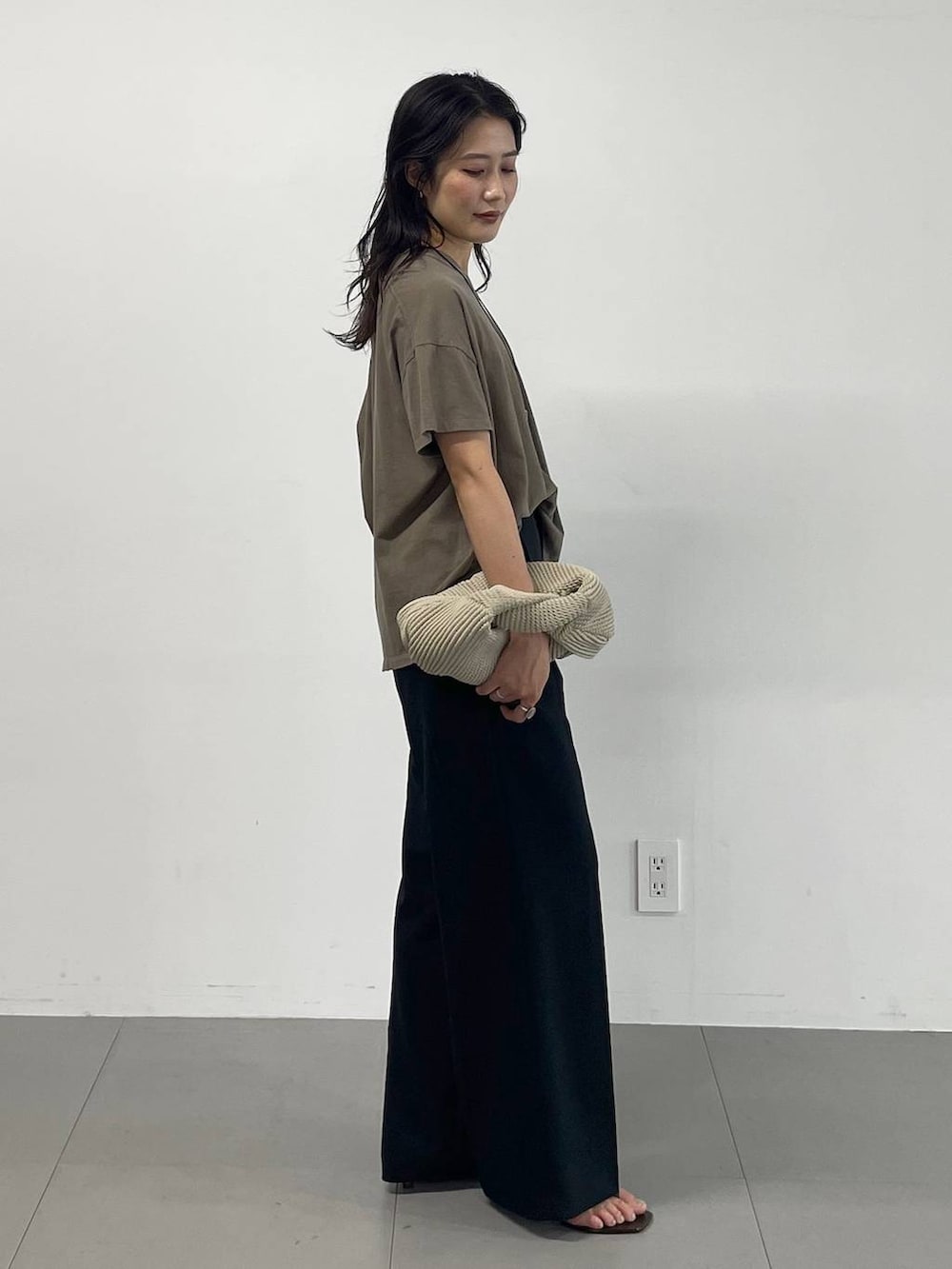 ブラック系のスラックス、グリーン系のTシャツ/カットソー、ブラック系のサンダルを着用したレディースの夏コーディネートの3枚目の写真