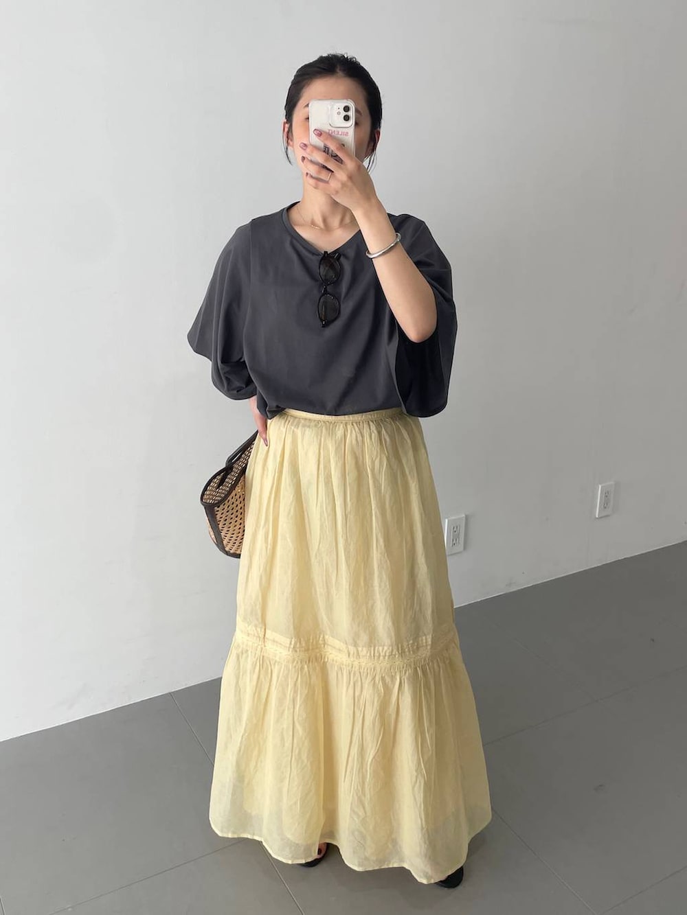 ベージュ系のかごバッグ、ブラック系のスリッポン、グレー系のTシャツ/カットソーを着用したレディースの夏コーディネートの5枚目の写真