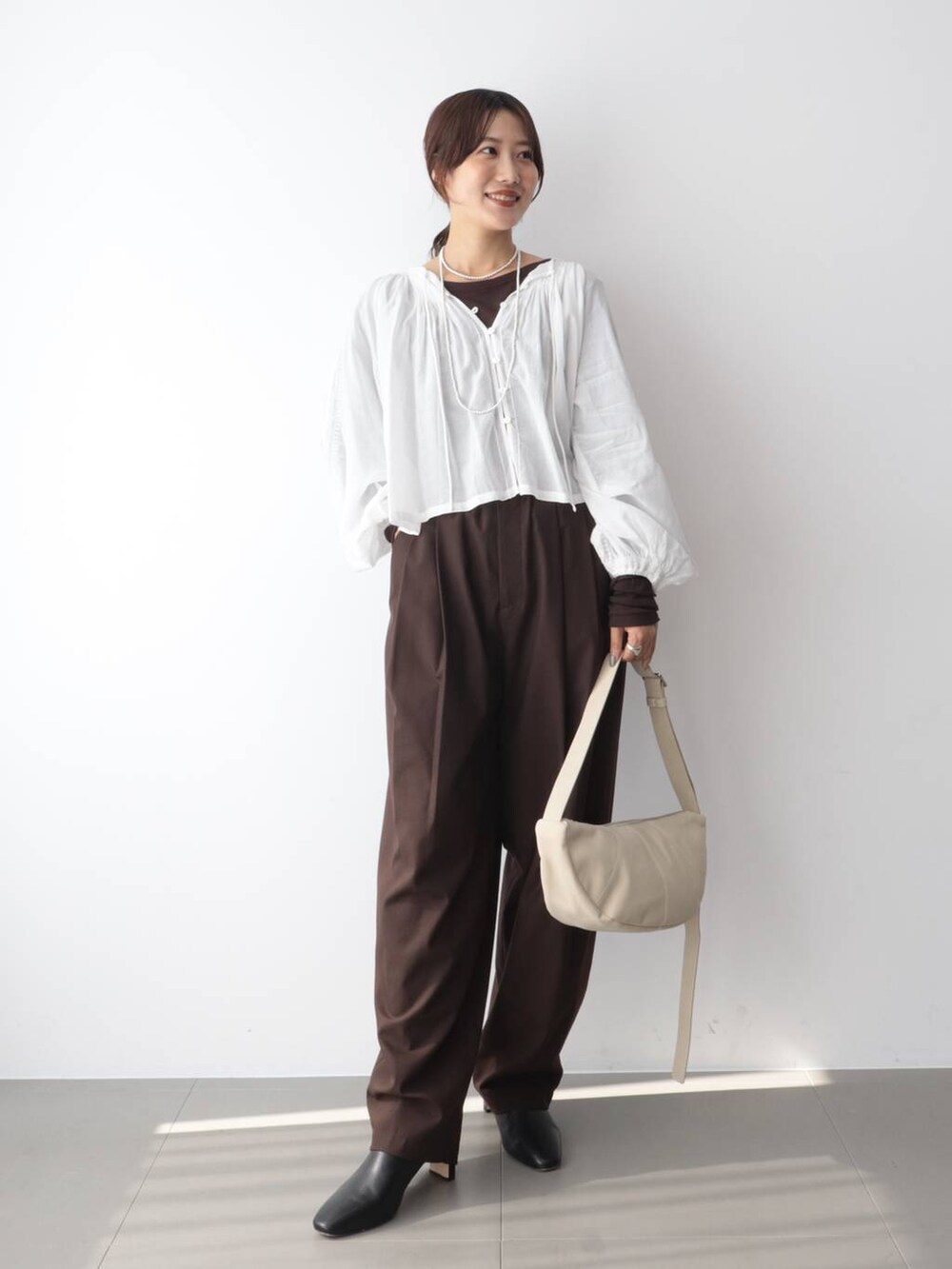 ホワイト系のシャツ/ブラウス、ブラウン系のその他パンツ、ホワイト系のショルダーバッグを着用したレディースの秋コーディネートの2枚目の写真