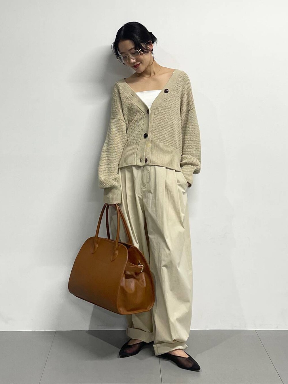 ブラック系のパンプス、ベージュ系のカーディガン/ボレロ、ブラウン系のボストンバッグを着用したレディースの春コーディネートの2枚目の写真