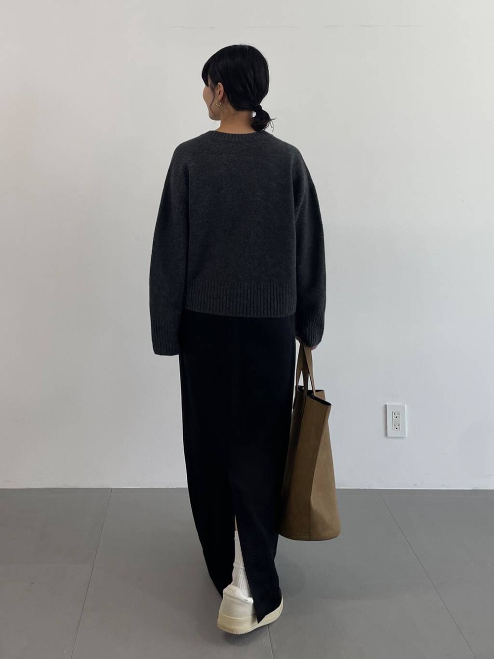 ブラウン系のトートバッグ、ブラック系のスカート、グレー系のニット/セーターを着用したレディースの冬コーディネートの5枚目の写真