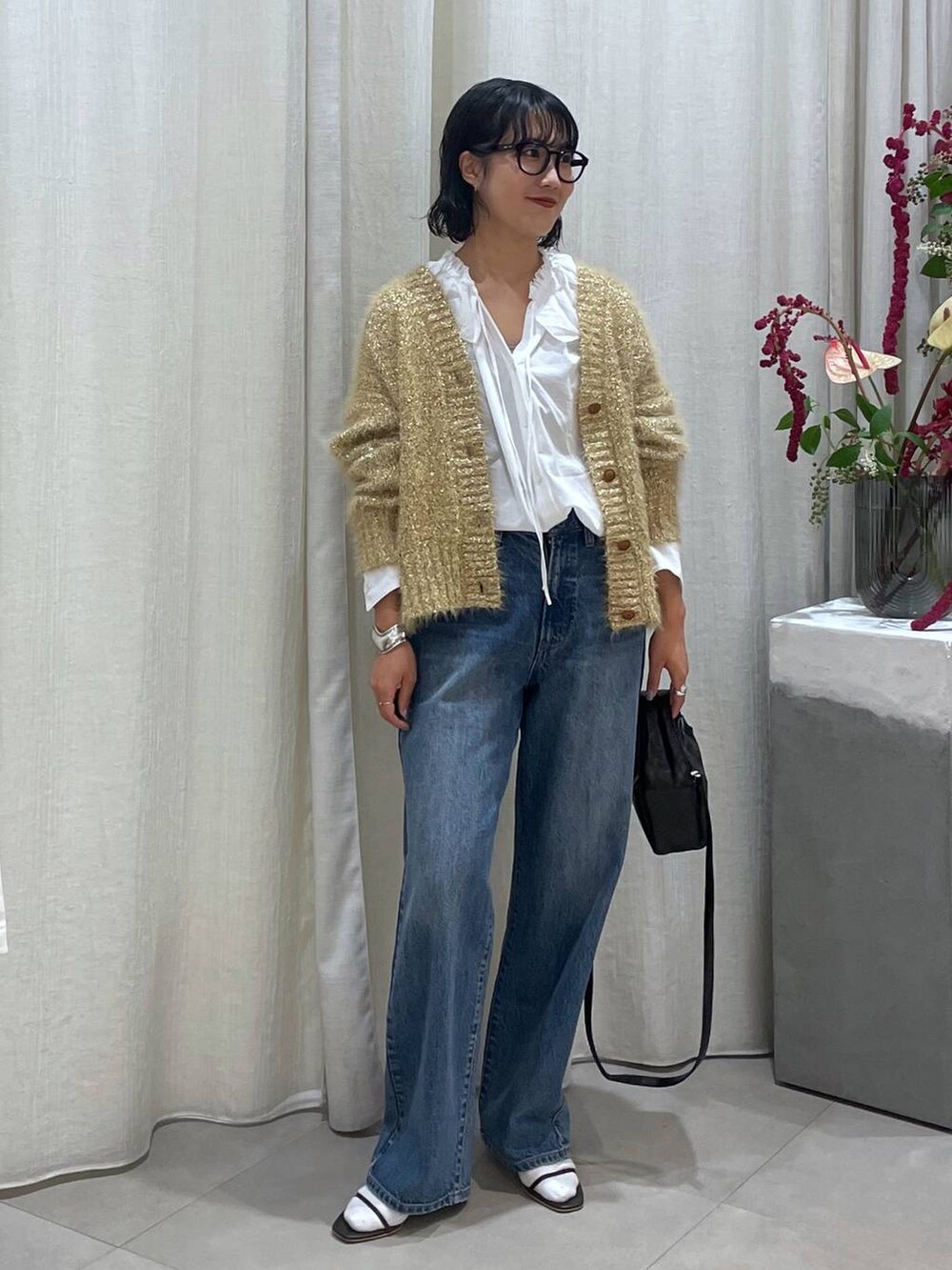 ブルー系のデニムパンツ、ブラウン系のサンダル、ホワイト系のシャツ/ブラウスを着用したレディースの秋コーディネートの2枚目の写真