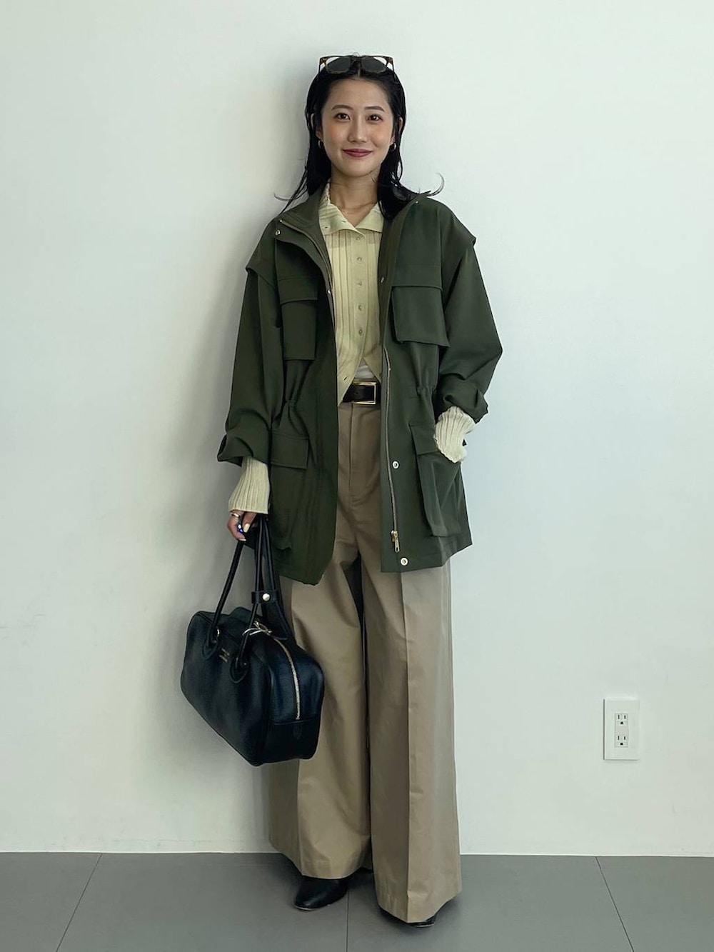 ブラック系のブーツ、ベージュ系のチノパンツ、イエロー系のニット/セーターを着用したレディースの冬コーディネートの2枚目の写真