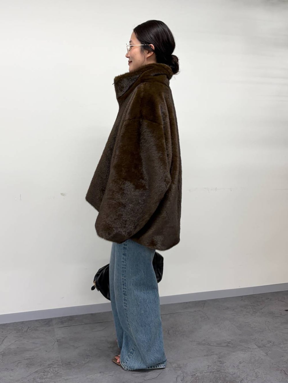 グレー系のニット/セーター、ブラウン系のムートンコート、ベージュ系のサンダルを着用したレディースの秋コーディネートの3枚目の写真