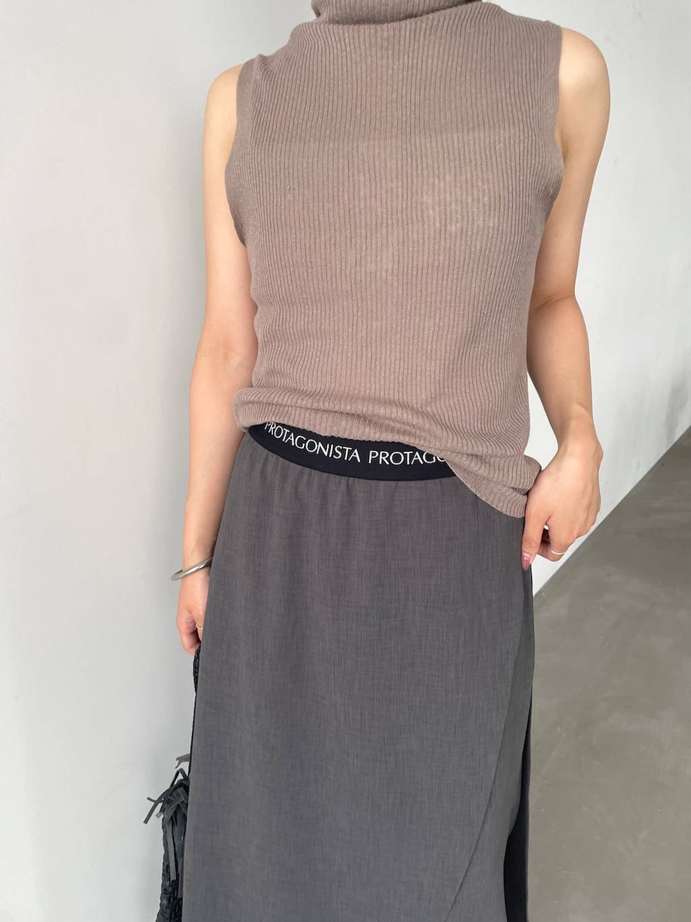 ブラック系のショルダーバッグ、ブラウン系のニット/セーター、グレー系のその他パンツを着用したレディースの夏コーディネートの2枚目の写真