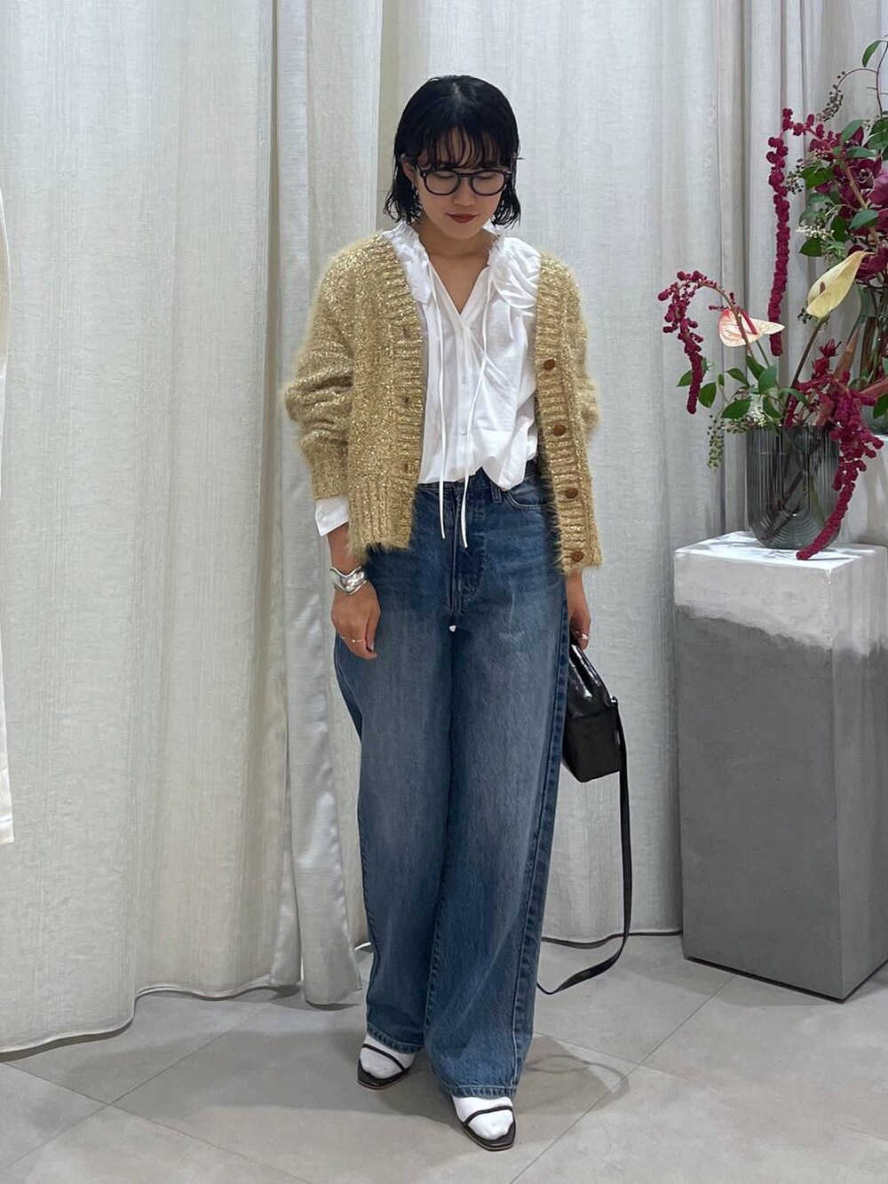 ブルー系のデニムパンツ、ブラウン系のサンダル、ホワイト系のシャツ/ブラウスを着用したレディースの秋コーディネートの3枚目の写真