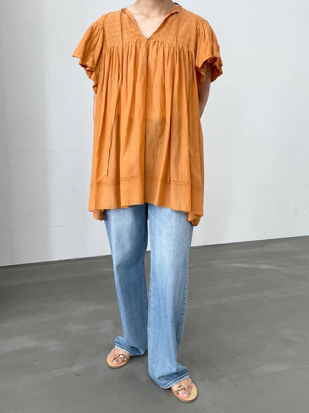 ベージュ系のTシャツ/カットソー、ブルー系のデニムパンツ、ブラウン系のサンダルを着用したレディースの夏コーディネートの4枚目の写真