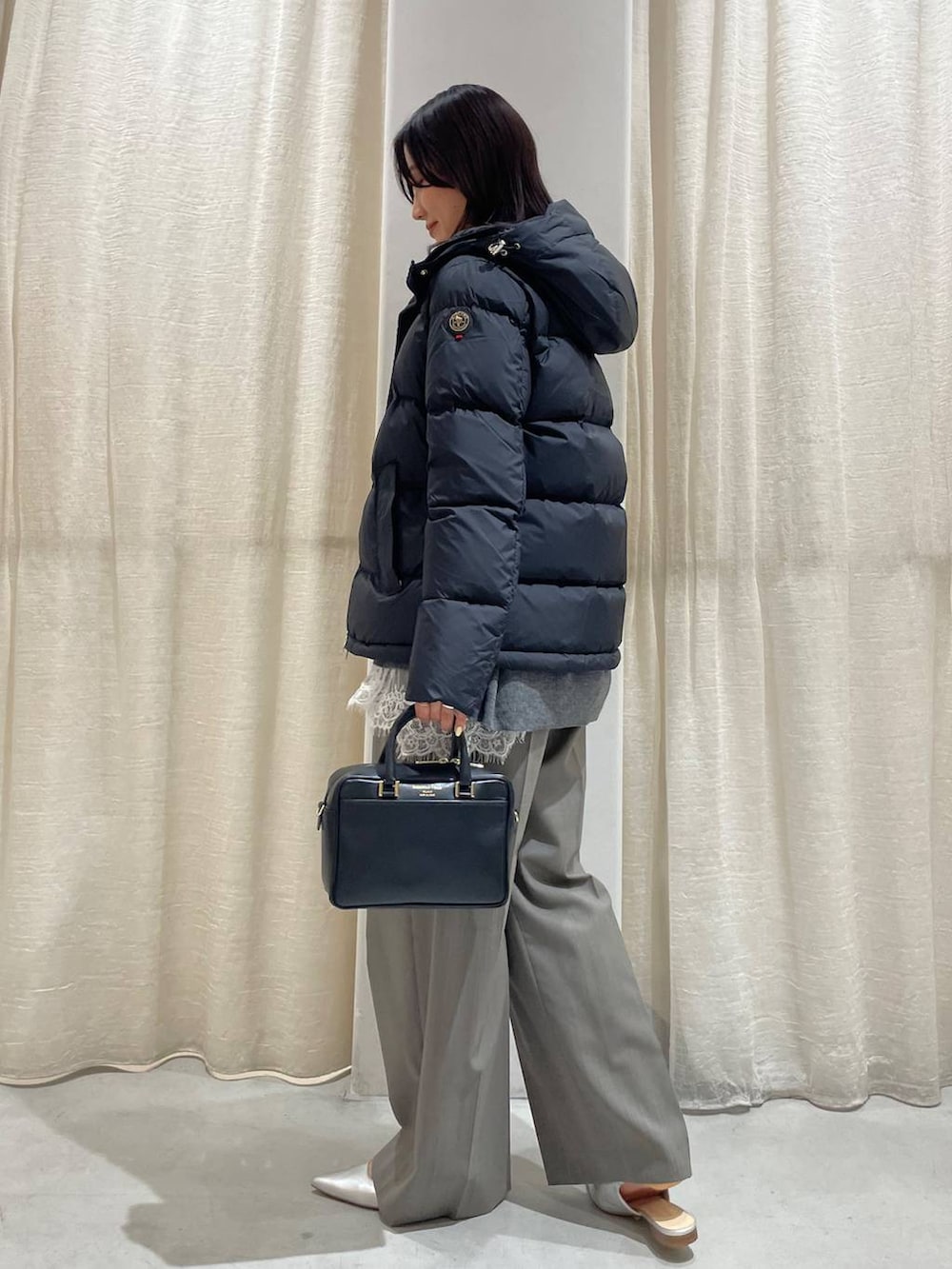 グレー系のスラックス、グレー系のニット/セーター、ホワイト系のキャミソールを着用したレディースの秋コーディネートの3枚目の写真