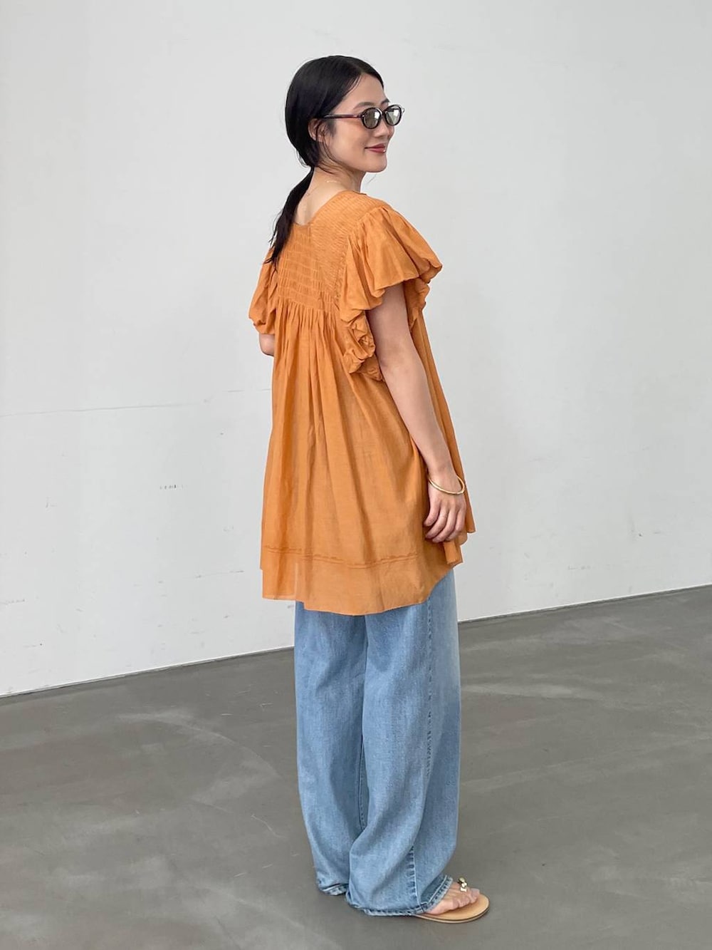 ベージュ系のTシャツ/カットソー、ブルー系のデニムパンツ、ブラウン系のサンダルを着用したレディースの夏コーディネートの3枚目の写真