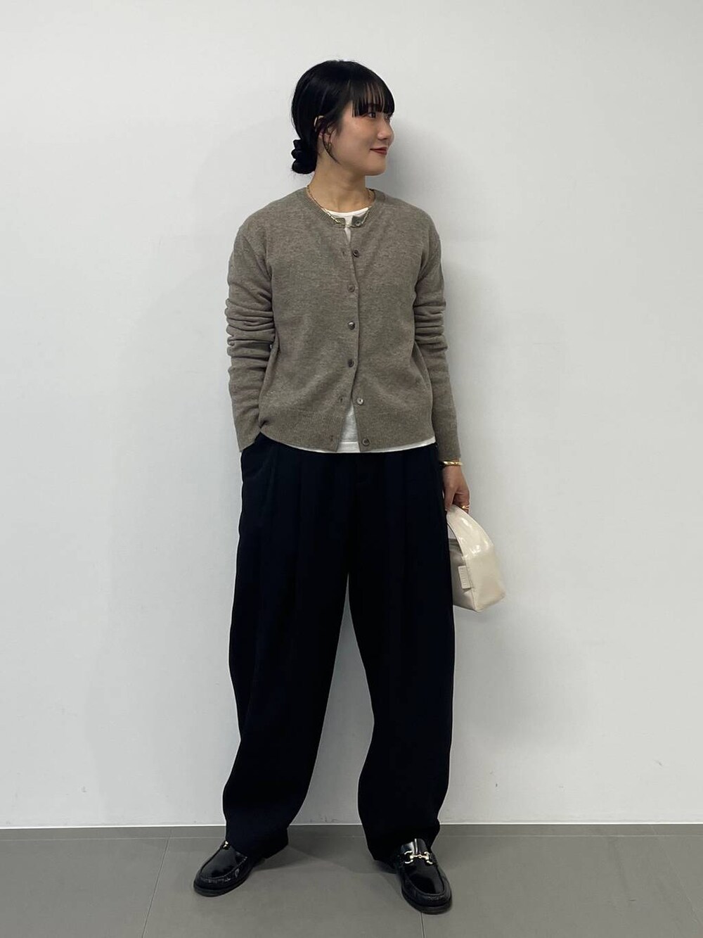 ホワイト系のハンドバッグ、ブラック系のその他パンツ、グリーン系のニット/セーターを着用したレディースの秋コーディネートの3枚目の写真