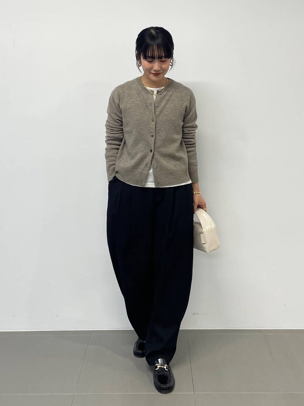 ホワイト系のハンドバッグ、ブラック系のその他パンツ、グリーン系のニット/セーターを着用したレディースの秋コーディネートの2枚目の写真