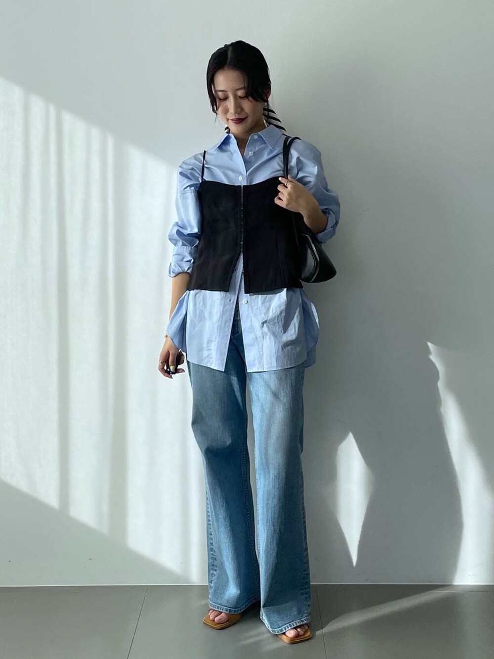 ブラック系のハンドバッグ、ブルー系のシャツ/ブラウス、ブルー系のデニムパンツを着用したレディースの冬コーディネートの2枚目の写真