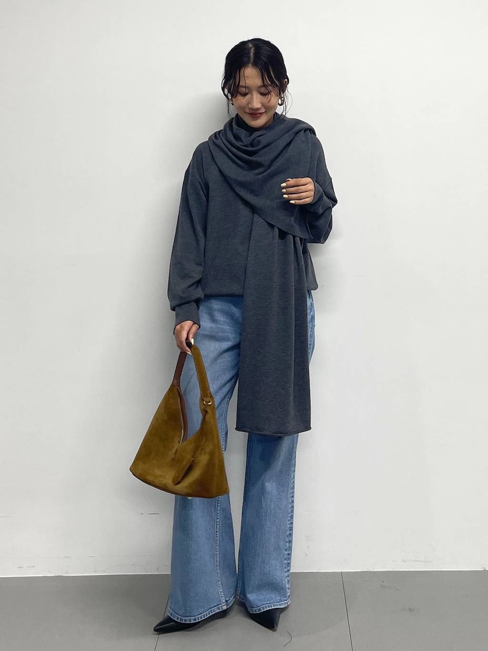 ブラック系のブーツ、ブラウン系のハンドバッグ、グレー系のニット/セーターを着用したレディースの冬コーディネートの2枚目の写真