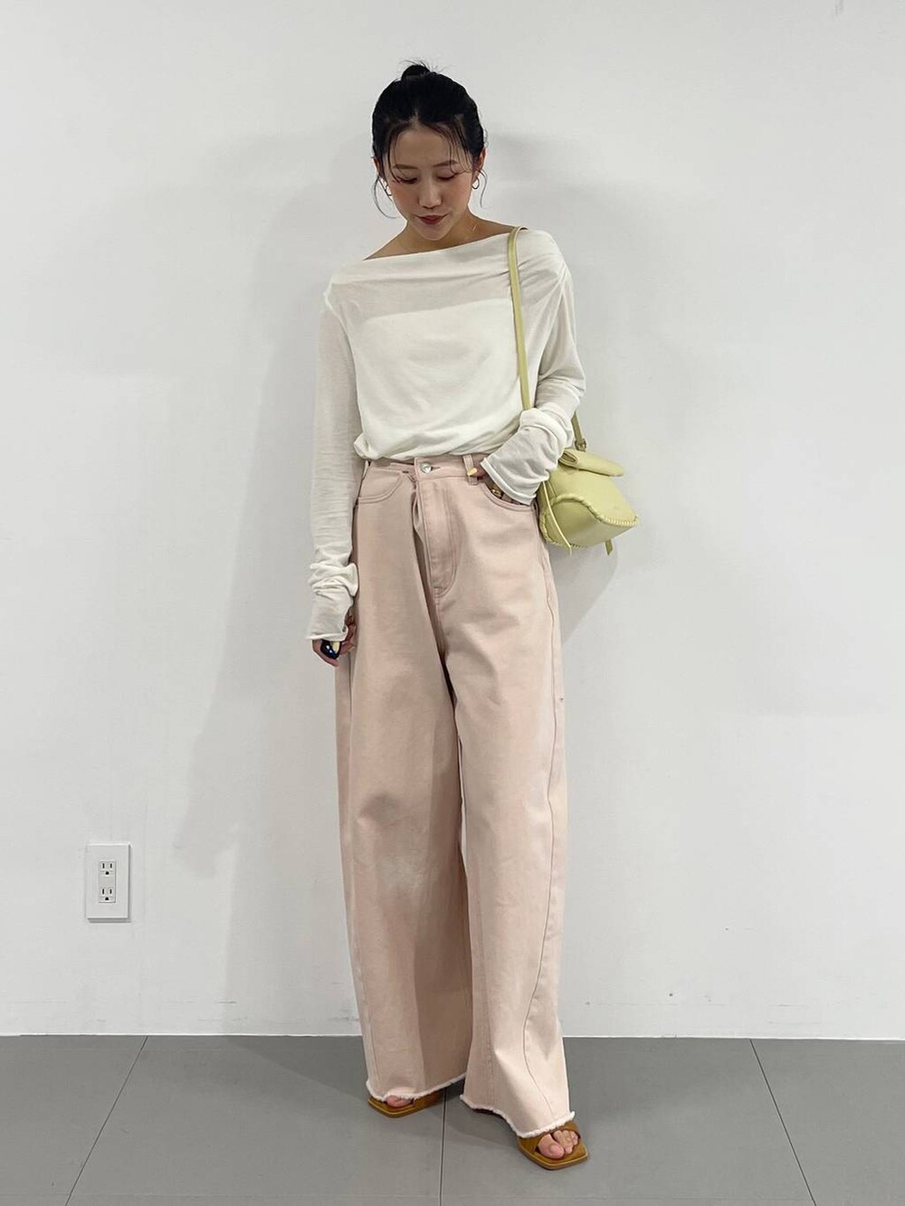 ピンク系のデニムパンツ、イエロー系のハンドバッグ、ホワイト系のTシャツ/カットソーを着用したレディースの冬コーディネートの4枚目の写真