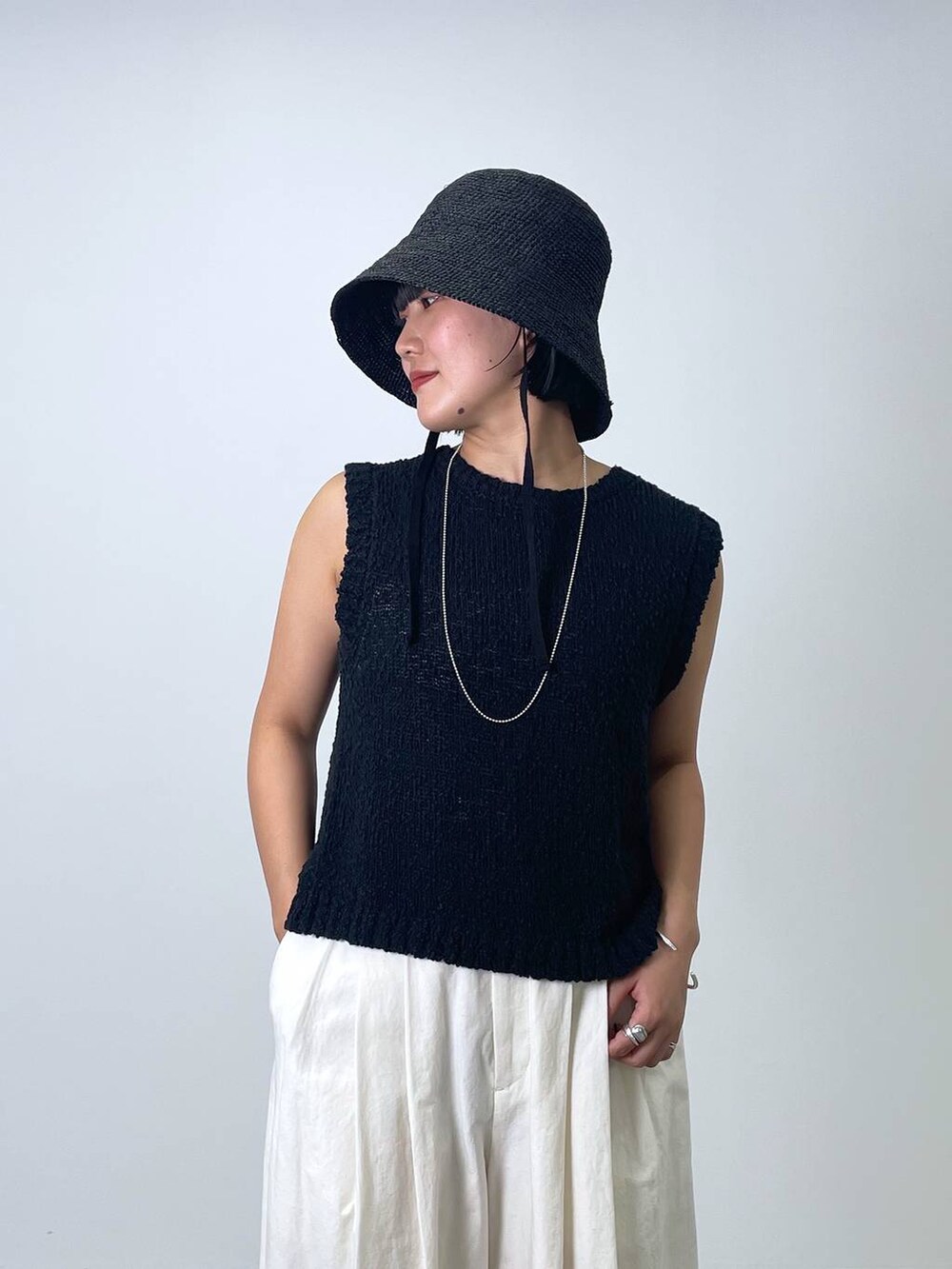 ブラック系のニット/セーター、ホワイト系のその他パンツ、ブラック系のハットを着用したレディースの春コーディネートの3枚目の写真