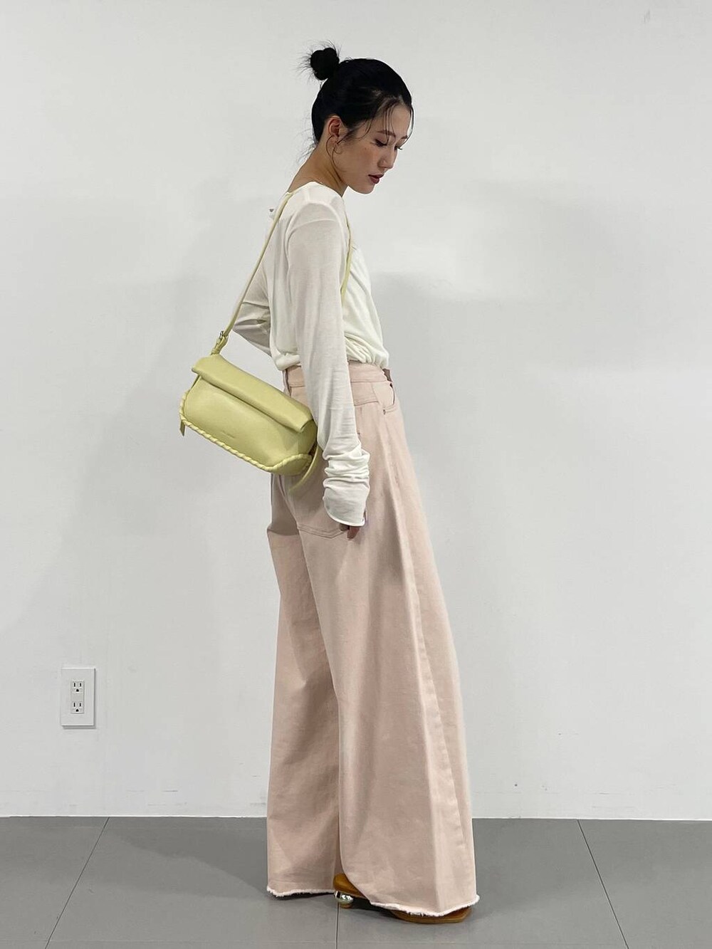 ピンク系のデニムパンツ、イエロー系のハンドバッグ、ホワイト系のTシャツ/カットソーを着用したレディースの冬コーディネートの5枚目の写真