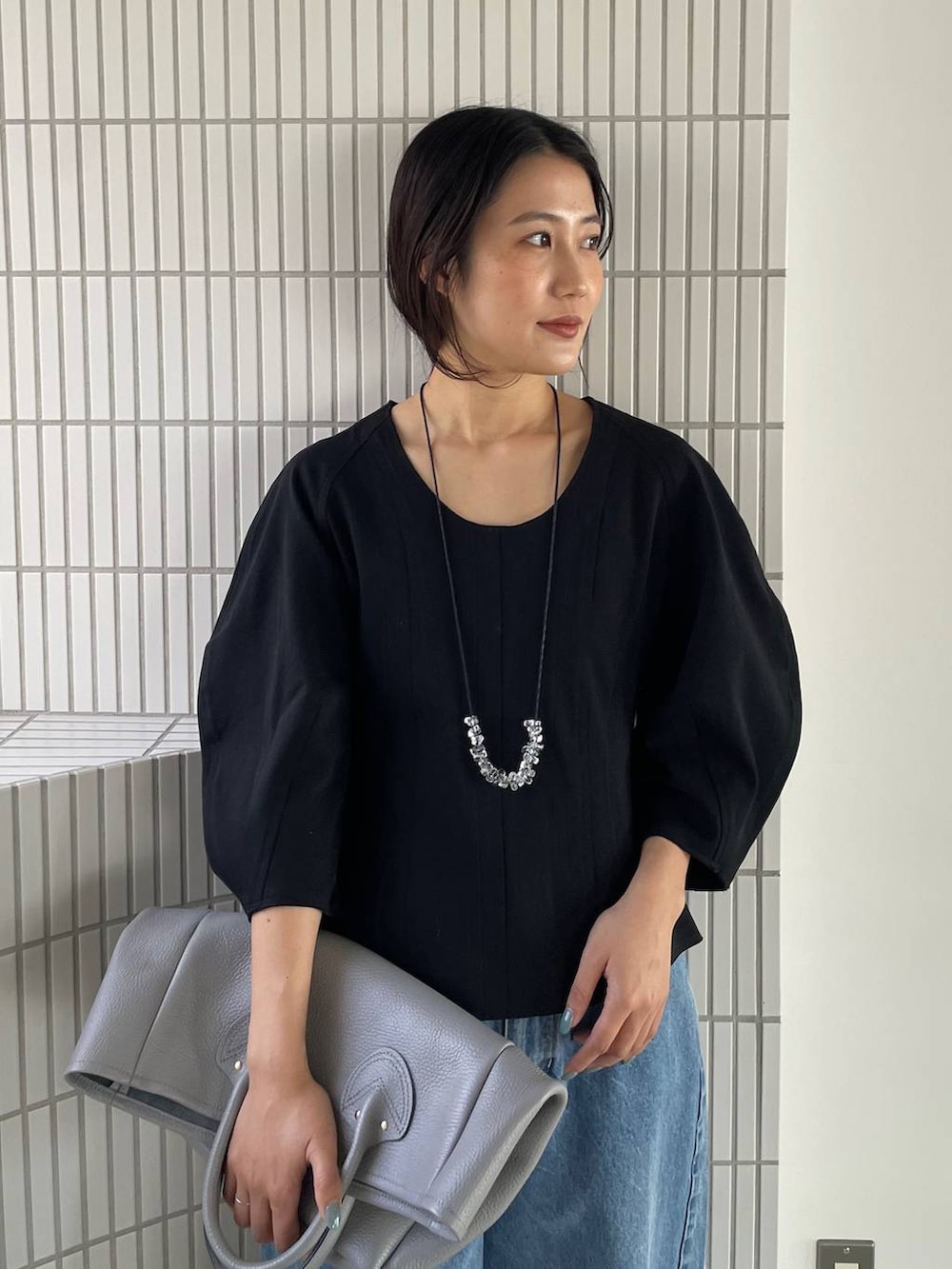 ブルー系のデニムパンツ、ブラック系のTシャツ/カットソー、グレー系のショルダーバッグを着用したレディースの春コーディネートの5枚目の写真