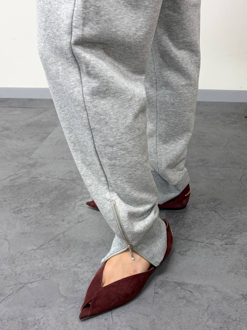 レッド系のパンプス、グレー系のスウェットパンツ、ブラック系のボストンバッグを着用したレディースの秋コーディネートの5枚目の写真