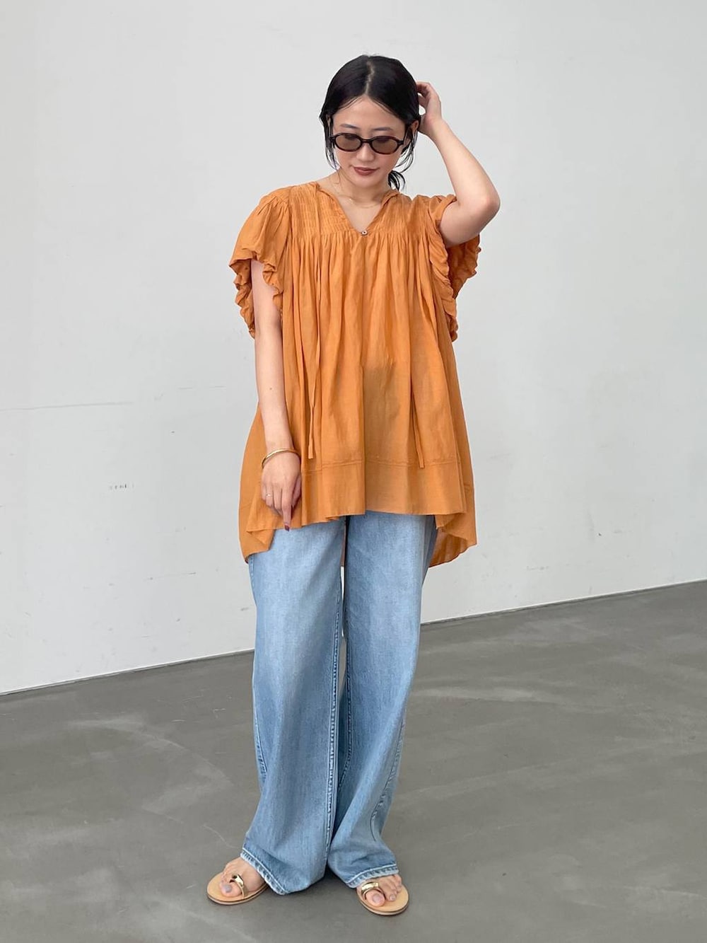 ベージュ系のTシャツ/カットソー、ブルー系のデニムパンツ、ブラウン系のサンダルを着用したレディースの夏コーディネートの2枚目の写真