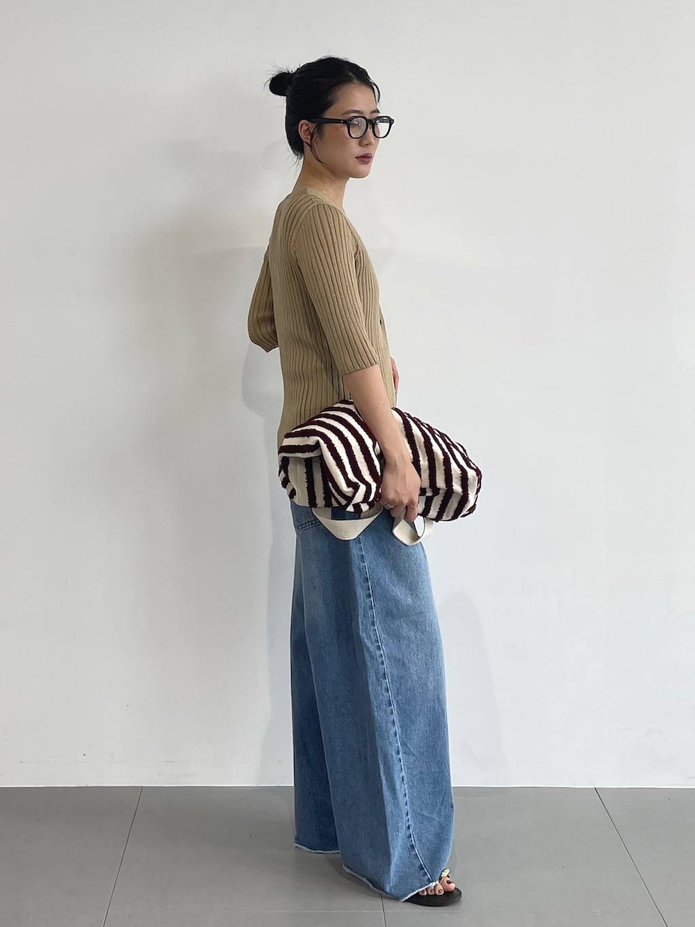 ブルー系のデニムパンツ、ブラック系のサンダル、ベージュ系のカーディガン/ボレロを着用したレディースの夏コーディネートの3枚目の写真